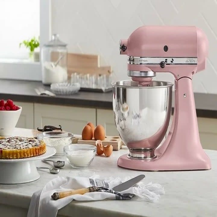 Pink stand mixer on a counter with various baking tools and ingredients and a baked tart