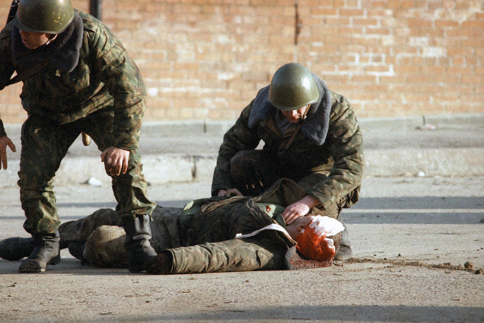 FILE - Two Russian soldiers help their wounded comrade who is down with a head injury during the fighting between hard-liners and the Russian Army outside the parliament in Moscow on Oct. 4, 1993. Three decades ago, the world held its breath as tanks blasted the Russian parliament building in central Moscow while the Kremlin moved to flush out rebellious lawmakers in a crisis that shaped the country's post-Soviet history. (AP Photo/Tanya Makeyeva, File)