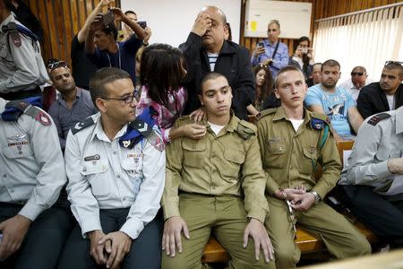 The father (C, back) of Israeli soldier Elor Azaria (C, seated), who is charged with manslaughter by the Israeli military after he shot a wounded Palestinian assailant as he lay on the ground in Hebron on March 24, prays behind him in a military court during a remand hearing for his case, near the southern Israeli city of Kiryat Malachi, March 31, 2016. REUTERS/Amir Cohen