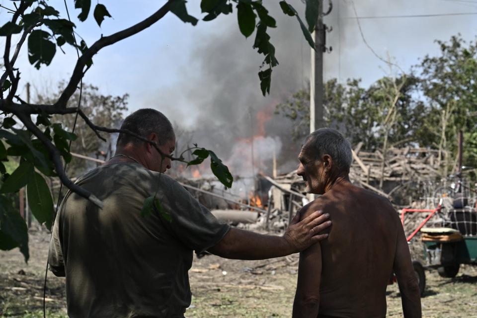 Local residents stand next to a burning private house a day after a missile attack in Myrnograd, Donetsk region, (AFP via Getty Images)