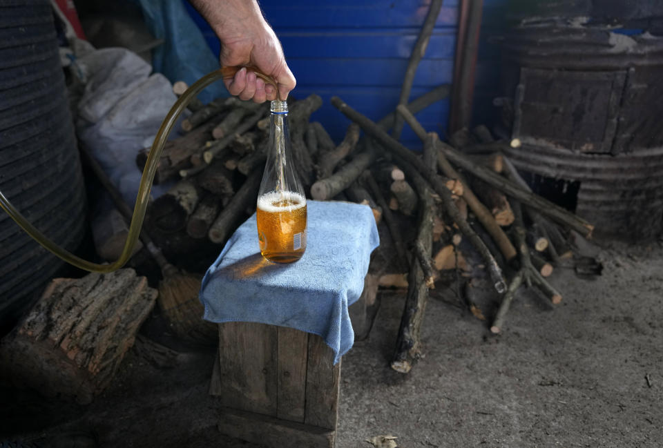 Miroslav Milosevic pours plum brandy into the bottle in the village of Rozanci, 20 kilometers south of Belgrade, Serbia, Friday, Nov. 11, 2022. The U.N.'s culture and education organization is set later this month to review Serbia's bid to include "social practices and knowledge related to the preparation and use of the traditional plum spirit - sljivovica" on the list of world intangible cultural heritage. (AP Photo/Darko Vojinovic)