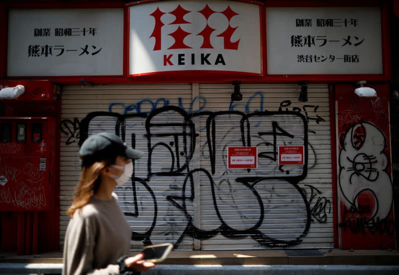 A woman wearing a protective face mask, following an outbreak of the coronavirus disease (COVID-19), walks in front of a temporary closed ramen noodle restaurant in Tokyo