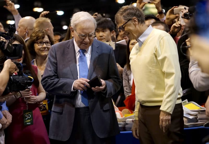 FILE PHOTO: Berkshire Hathaway CEO Warren Buffett gets his wallet out to pay a bet to Microsoft co-founder Bill Gates after participating in a newspaper throwing contest prior to the Berkshire annual meeting in Omaha