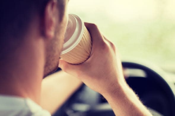 transportation and vehicle concept - man drinking coffee while driving the car