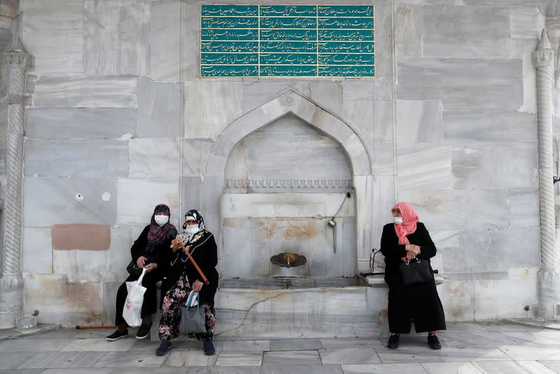 FILE PHOTO: Women wearing protective face masks sit at an old fountain in Istanbul