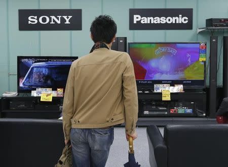 A man looks at Sony and Panasonic TV sets at an electronics shop in Tokyo May 15, 2012. Sony Corp and Panasonic Corp are in talks to develop the technology to mass produce next-generation OLED televisions, sources close to the matter said on Tuesday, but may already be running to catch up with South Korean rivals in a technology widely seen replacing current LCD TVs. REUTERS/Kim Kyung-Hoon (JAPAN - Tags: BUSINESS SCIENCE TECHNOLOGY) - RTR322QQ