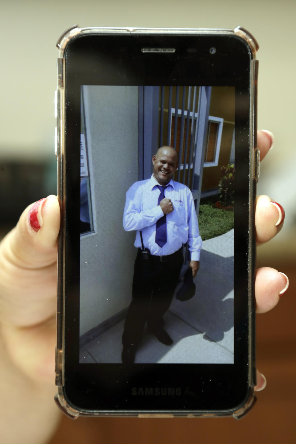 In this Wednesday, Feb. 26, 2020 photo, Yarelis Gutierrez Barrios holds up a cell phone photo at her home in Tampa, Fla., of her partner Roylan Hernandez Diaz, a Cuban asylum seeker who hanged himself in a Louisiana prison. An Associated Press investigation into Hernandez’s death last October found neglect and apparent violations of government policies by jailers under U.S. Immigration and Customs Enforcement. (AP Photo/Chris O'Meara)