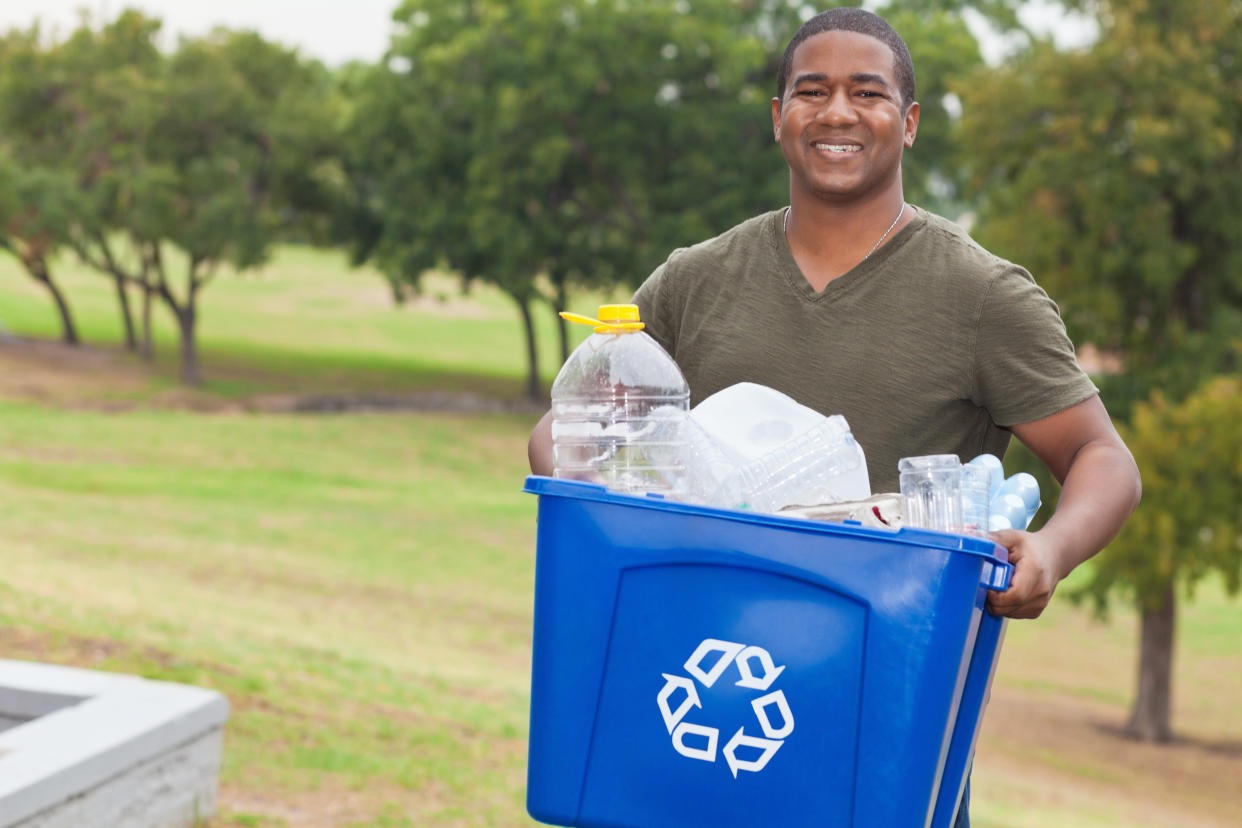 Man holding a recycle bin full of garbage.