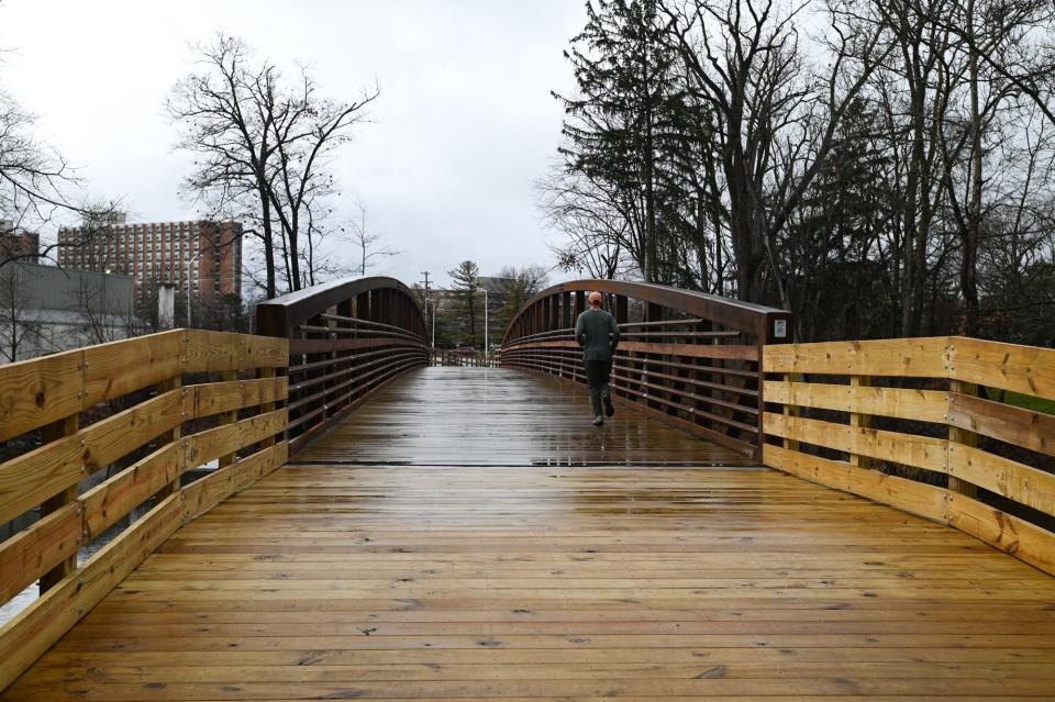 A jogger runs over the newly built bridge over the Red Cedar River in East Lansing on the new MSU-to-Lake Lansing trail, Friday, Dec. 29, 2023.