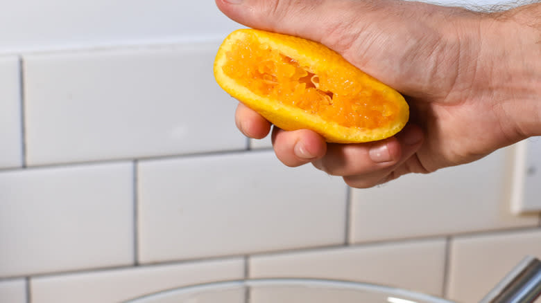 juicing an orange into a bowl
