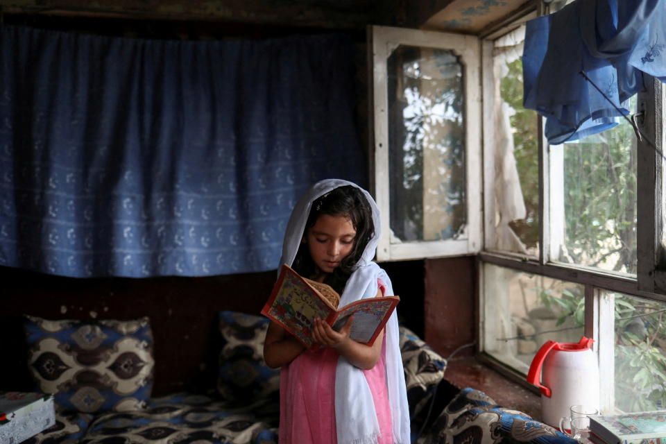 Una niña lee en libro dentro de su casa de Kabul, en Afganistán. (REUTERS/Ali Khara)