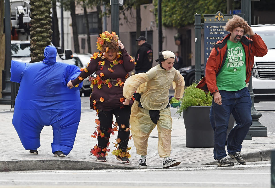 A cold wind threatens to blow away Halloween revelers crossing Canal Street in New Orleans, La. Thursday, Oct. 31, 2019. The U.S. National Weather Service issued a Wind Advisory 10:00 PM on Halloween. (Max Becherer/The Advocate via AP)