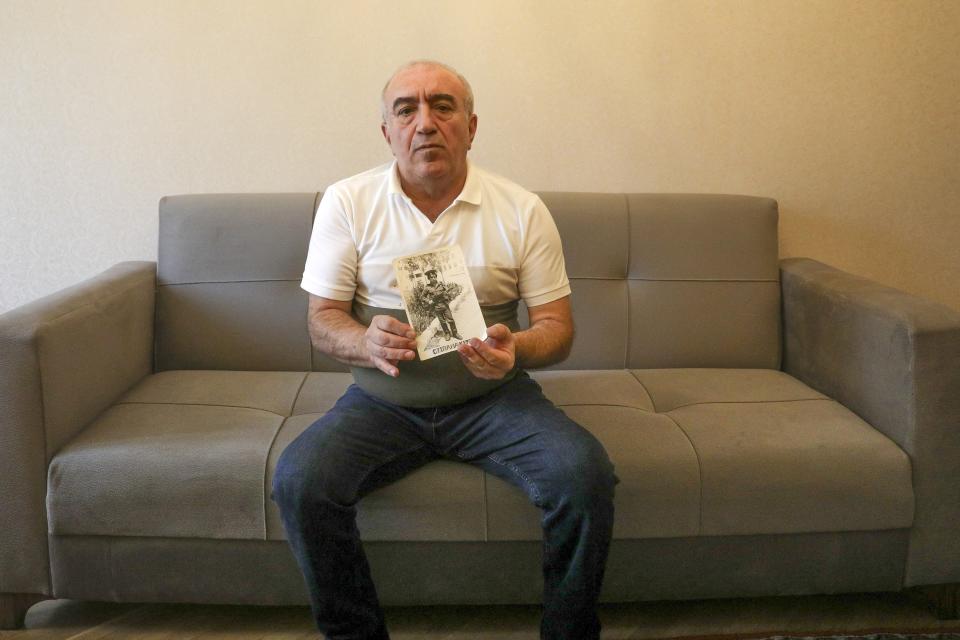 Former Nazim Valiyev shows a photo of him years ago of himself in the military during Soviet time as he sits in his home in Baku, Azerbaijan, Saturday, Oct. 14, 2023. Valiyev is among the estimated 700,000 Azerbaijanis who fled or were forced out of the region amid violence that flared beginning in 1988 and then flared into an outright war that ended in 1994 with the region under the control of ethnic Armenian forces supported by Armenia. (AP Photo/Aziz Karimov)
