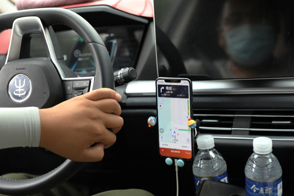 A driver of Chinese ride-hailing service Didi drives with a phone showing a navigation map on Didi's app, in Beijing, China July 5, 2021. REUTERS/Tingshu Wang