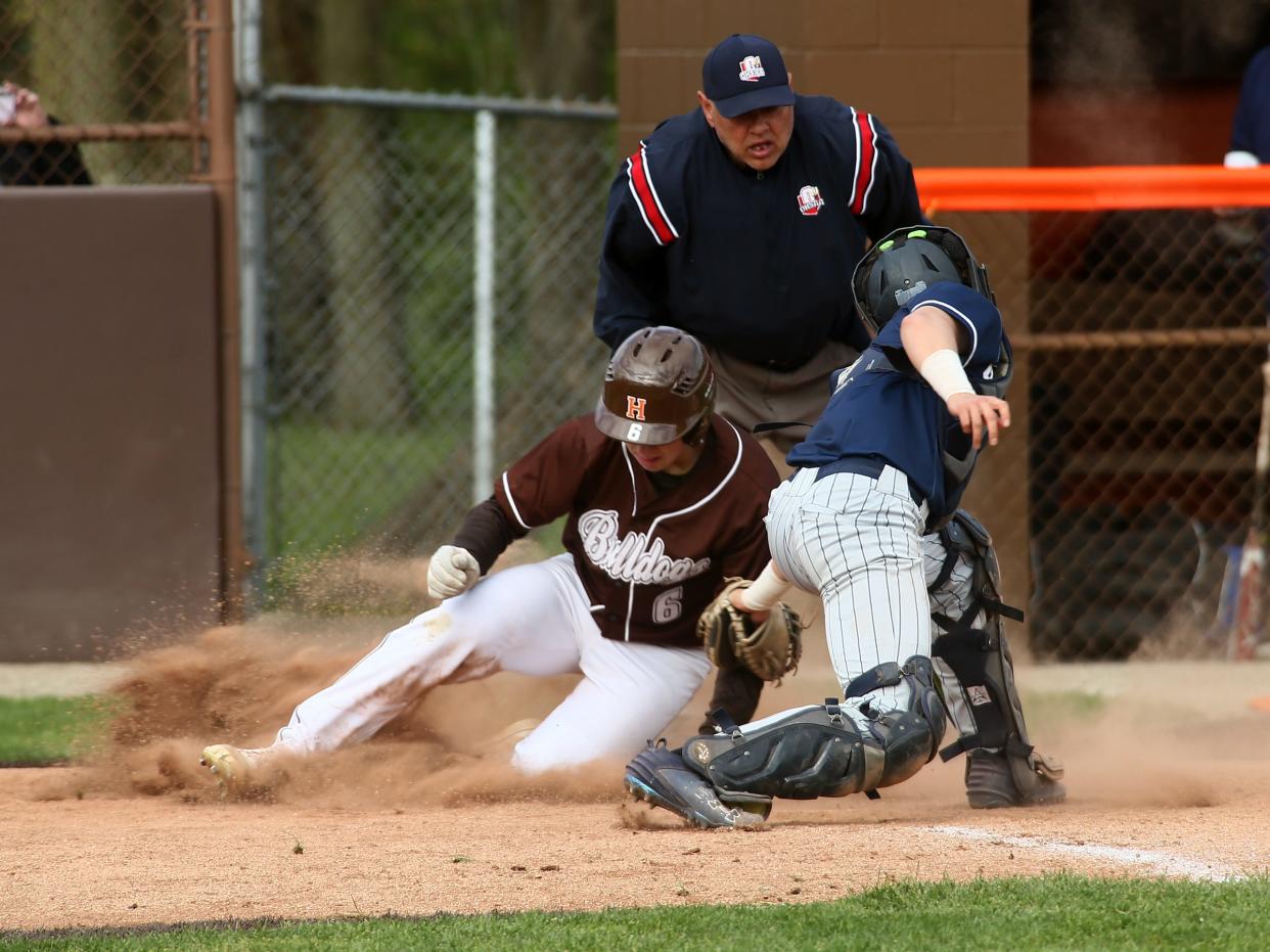 Heath's Wyatt Binckley slides safely past Granville's Jacob Smith to score during the Bulldogs' 7-1 victory on Wednesday, April 24, 2024.