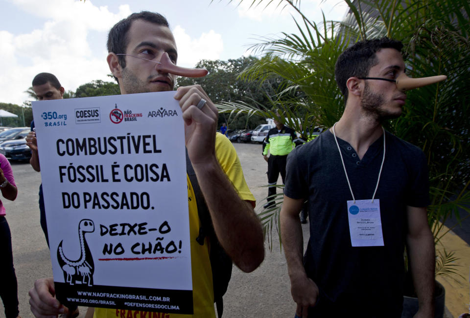 Demonstrator holds a sign that reads in Portuguese "Fossil fuel, it is a thing of the past. Leave it on the floor" during a protest outside the Latin America and Caribbean Climate Week workshop in Salvador, Bahia state, Brazil, Wednesday, Aug. 21, 2019. Brazil is hosting a week-long UN workshop on climate change in the northern state of Bahia, which the environment minister tried to cancel earlier this year. (AP Photo/Arisson Marinho)