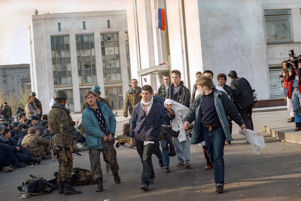 FILE - Hard-line defenders carrying white flags and a wounded comrade on a stretcher surrender to forces loyal to Boris Yeltsin in Moscow on Oct. 4, 1993. Three decades ago, the world held its breath as tanks blasted the Russian parliament building in central Moscow while the Kremlin moved to flush out rebellious lawmakers in a crisis that shaped the country's post-Soviet history. (AP Photo/Diether Endlicher, File)