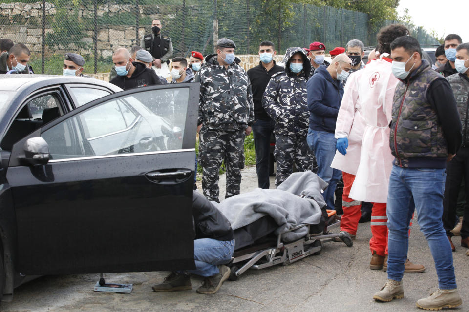 Body of Lokman Slim, a longtime Shiite political activist and researcher, who has been found dead in his car, lies on the ground as Lebanese security forces inspect the scene in Addoussieh village, in the southern province of Nabatiyeh, Lebanon, Thursday, Feb. 4, 2021. (AP Photo/Mohammed Zaatari)