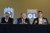 Jean-Michel Aulas, center, owner and president of the French soccer team Olympique Lyonnais, and OL Groupe's Gerard Houllier, left, listen as Bill Predmore, right, former owner of the National Women's Soccer League Reign FC team, speaks Thursday, Dec. 19, 2019, at a news conference in Tacoma, Wash. OL Groupe, the parent company of Olympique Lyonnais, is buying Reign FC, of the in a transaction expected to close in January 2020. Reign FC will continue to play its home games at Cheney Stadium, the venue it shares with the Triple-A minor league baseball team the Tacoma Rainiers. (AP Photo/Ted S. Warren)