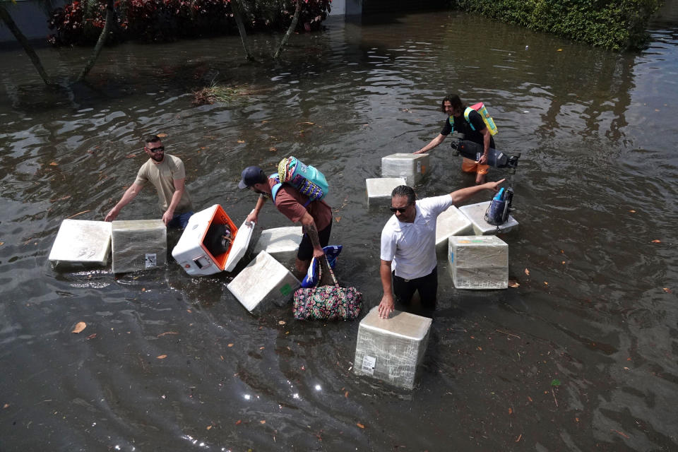 People try to save valuables as they wade through flood waters in the Edgewood neighborhood of Fort Lauderdale, Fla., on April 13, 2023.<span class="copyright">Joe Cavaretta—South Florida Sun-Sentinel/AP</span>