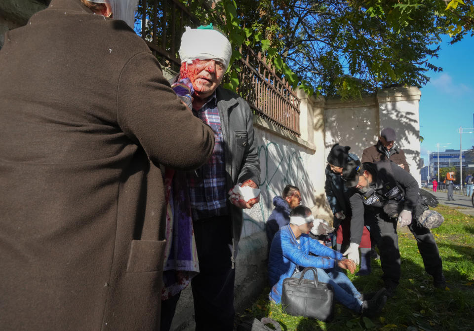 People receive medical treatment at the scene of Russian shelling in Kyiv, Ukraine, Monday, Oct. 10, 2022. Two explosions rocked Kyiv early Monday following months of relative calm in the Ukrainian capital. (AP Photo/Efrem Lukatsky)