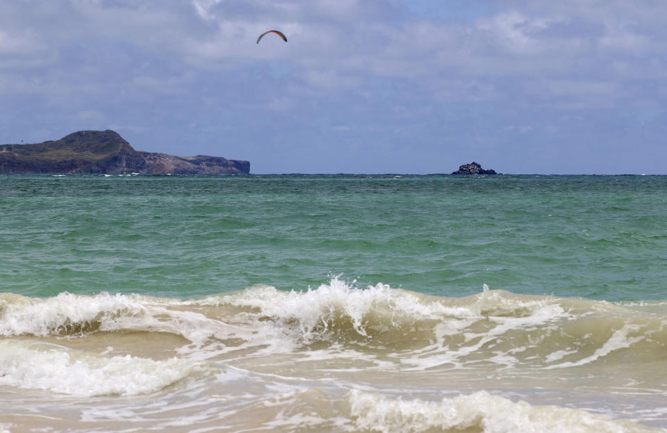 In this May 15, 2019, photo, a kitesurfer rides off Kailua Beach Park in Kailua, Hawaii. In Kailua, the sand is soft and white, the water is clear and calm, and the view is exactly what you might expect from a beach in the Hawaiian Islands. Those are among the reasons the beach has been selected as the best stretch of sand on an annual list of top U.S. beaches. Stephen Leatherman, a coastal scientist and professor at Florida International University, has been drafting the list under the alias "Dr. Beach" since 1991. (AP Photo/Caleb Jones)