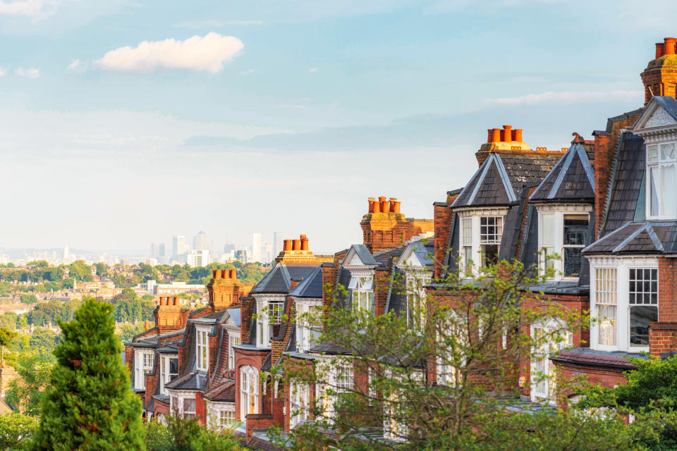 house price A row of traditional houses on a street in London's Muswell Hill suburb, located to the north of London, with views of the Canary Wharf on the horizon.