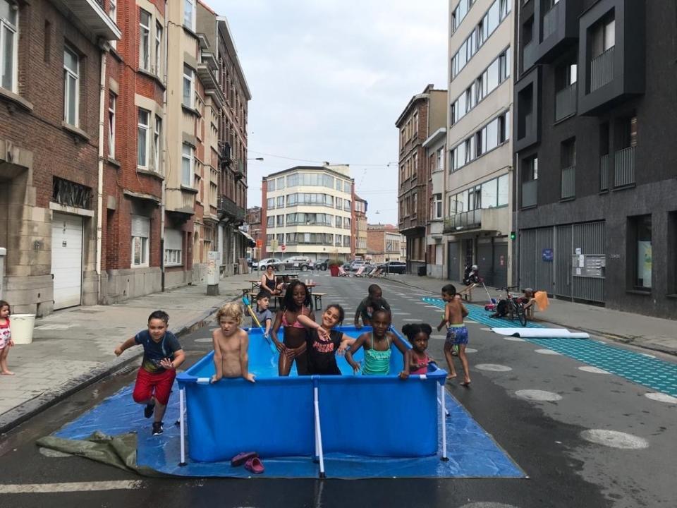 Children play in a pool which has been set up for them on the street in the Molenbeek district of Brussels, Tuesday, Aug. 11, 2020. Local authorities have been back and forth about banishing day trippers from the Belgian seaside, leaving inner city children and others with little alternative to deal with the current heatwave. (AP Photo/Mark Carlson)