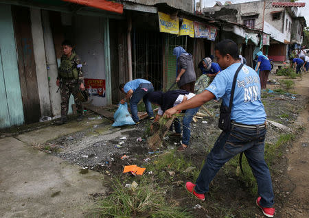 A soldier walks past members of the local government as they clear the area inside a war-torn Marawi city, southern Philippines October 19, 2017. REUTERS/Romeo Ranoco