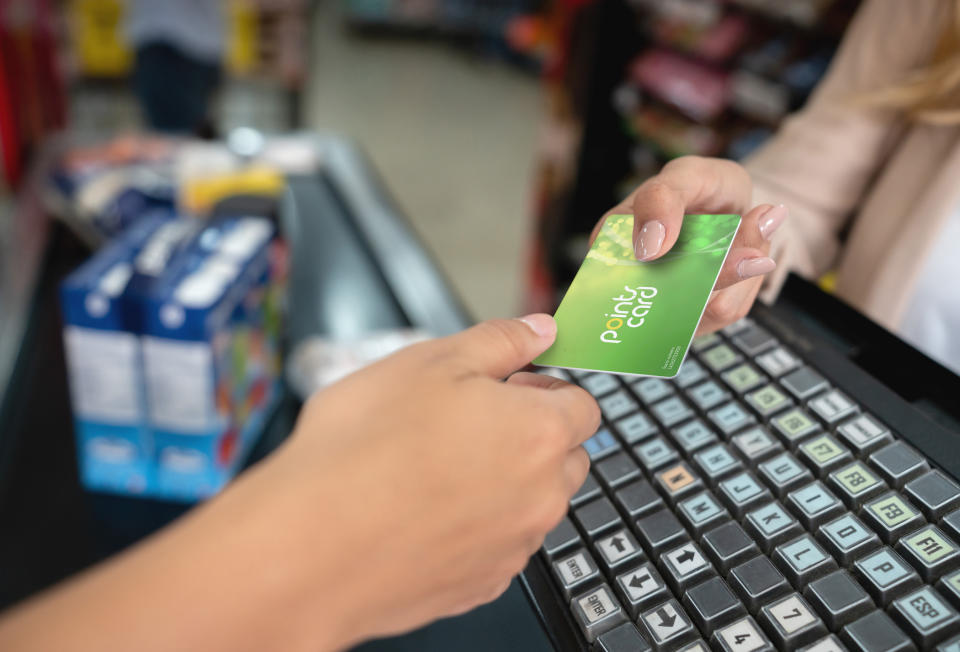 A person handing a points card to a cashier