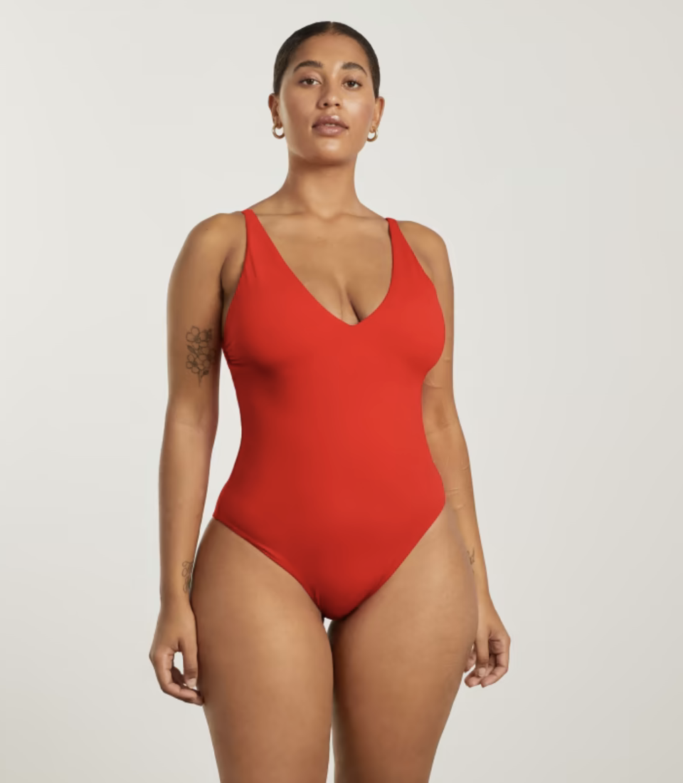 curving model with arm tattoo wearing red one-piece v-neck swimsuit, The V-Neck One-Piece by Everlane. 