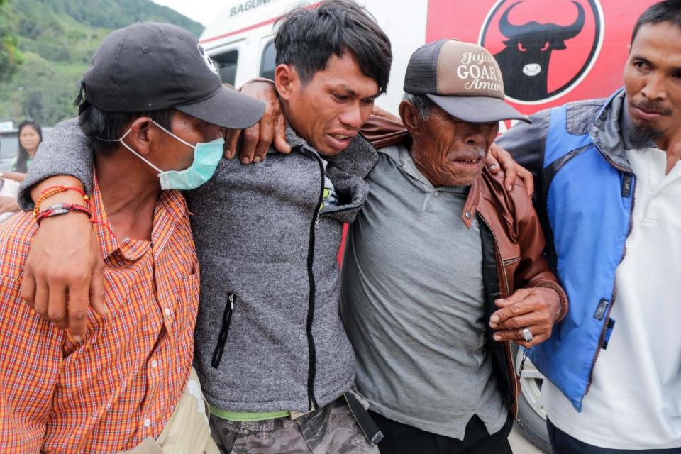 A person, who survived from a boat's sinking in Lake Toba, is helped by relatives (EPA)