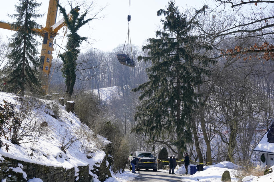 A car is lifted by crane during the recovery process on Monday Jan. 31, 2022 of a bus and other vehicles that were on a bridge when it collapsed Friday, in Pittsburgh's East End. (AP Photo/Gene J. Puskar)