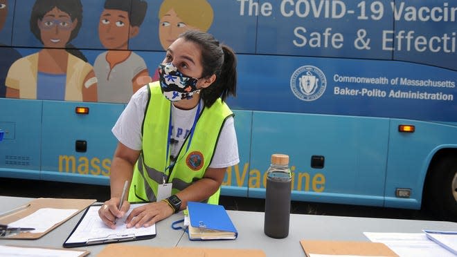Hannah Tavares, a Milford Health Department inspector, registers people at a COVID-19 vaccine bus last August at the Stacy Middle School.