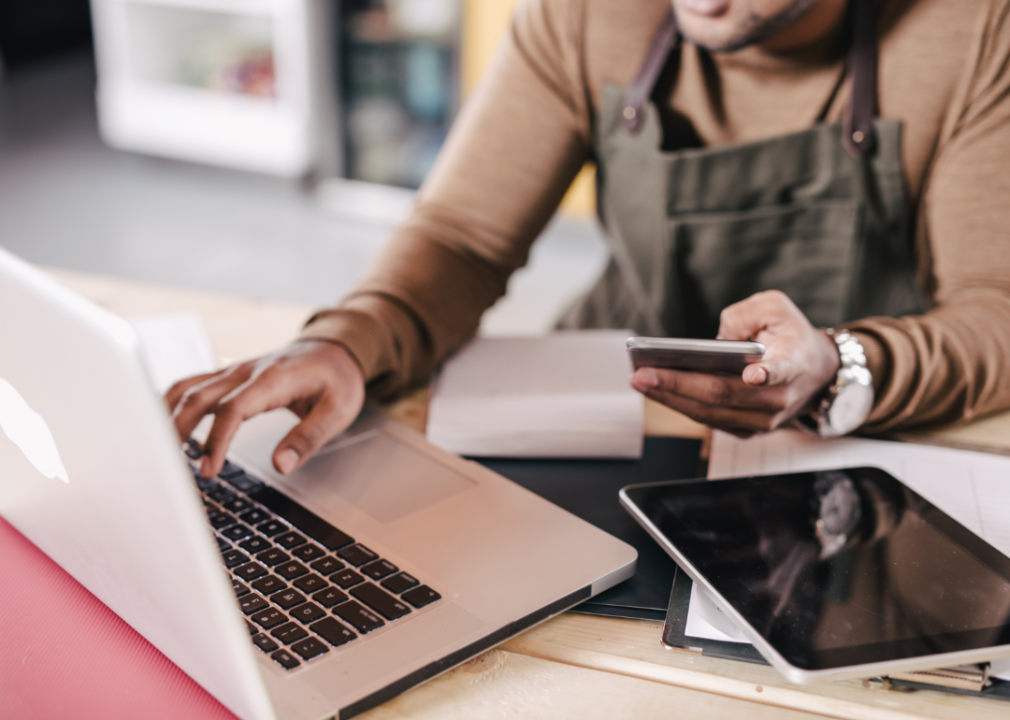 hands and arms of person using phone and laptop