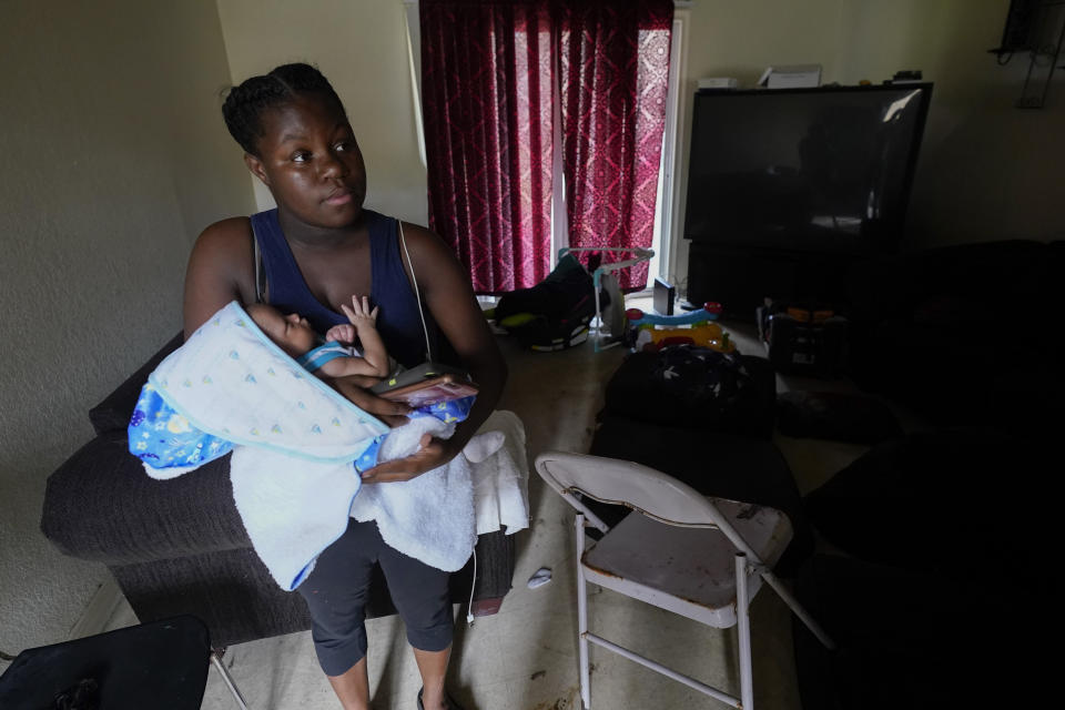 Sierra Patterson holds her three-week-old baby Tru Alexander in their flooded apartment where floodwaters reaches two feet inside, after Hurricane Sally moved through, Friday, Sept. 18, 2020, in , Fla. (AP Photo/Gerald Herbert)