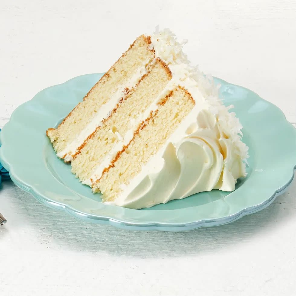 coconut layer cake with white frosting slice on plate