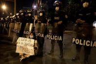 Una mujer se sienta en el suelo junto a una barrera policial en los alrededores del Congreso de Perú en Lima después de la renuncia del presidente interino Manuel Merino. Noviembre 15, 2020. REUTERS/Angela Ponce