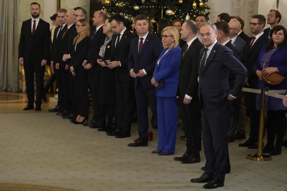 Poland's new Prime Minister Donald Tusk, right, stands next to ministers before the swearing-in ceremony at the presidential palace in Warsaw, Poland, Wednesday, Dec. 13, 2023. Donald Tusk was sworn in by the president in a ceremony where each of his ministers was also taking the oath of office. (AP Photo/Czarek Sokolowski)