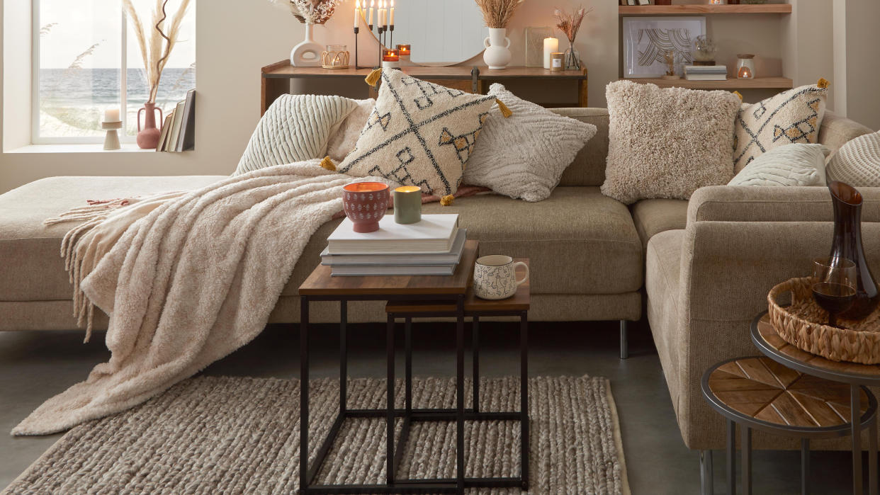  A cozy, neutrally-decorated living room with large sofa and assortment of lit candles 