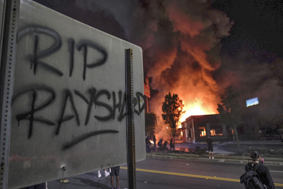 A Wendy's restaurant, background, burns Saturday, June 13, 2020, in Atlanta after demonstrators allegedly set it on fire. Demonstrators were protesting the death of Rayshard Brooks, a black man who was shot and killed by Atlanta police Friday evening following a struggle in the Wendy's drive-thru line. (Ben GrayAtlanta Journal-Constitution via AP)