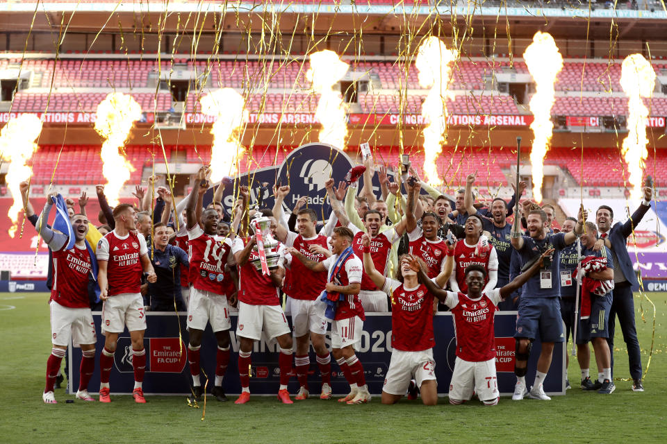 Pyrotechnics go off as Arsenal's players celebrate with the trophy after the FA Cup final soccer match between Arsenal and Chelsea at Wembley stadium in London, England, Saturday, Aug.1, 2020. (Catherine Ivill/Pool via AP)