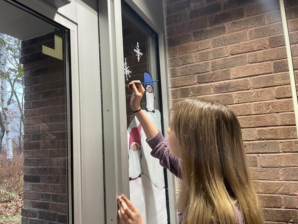 Port Huron Northern senior Azalea Hanton paints snowflakes on her winter window painting at Keewahdin Elementary School on Nov. 21, 2023.