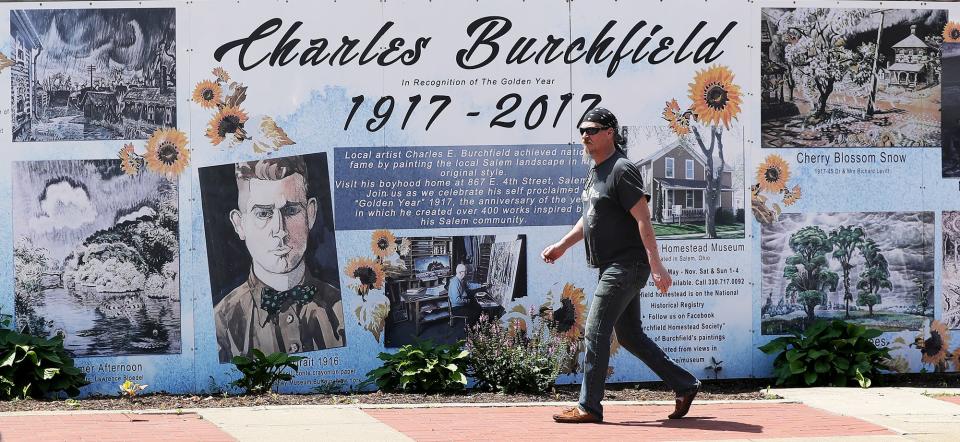 A Salem resident walks past a mural showcasing work from local artist Charles Burchfield.