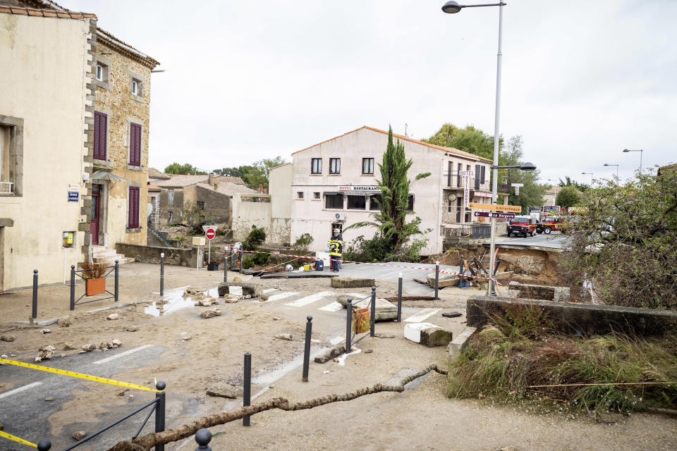 Rescue workers, background, secure the area by a collapsed bridge in the town of Villegailhenc, southern France, Monday, Oct.15, 2018. Flash floods tore through towns in southwest France, turning streams into raging torrents that authorities said killed several people and seriously injured at least five others. (AP Photo/Fred Lancelot)