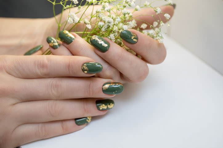 hands with beautiful khaki manicure and gold foil a woman is holding a branch with white flowers