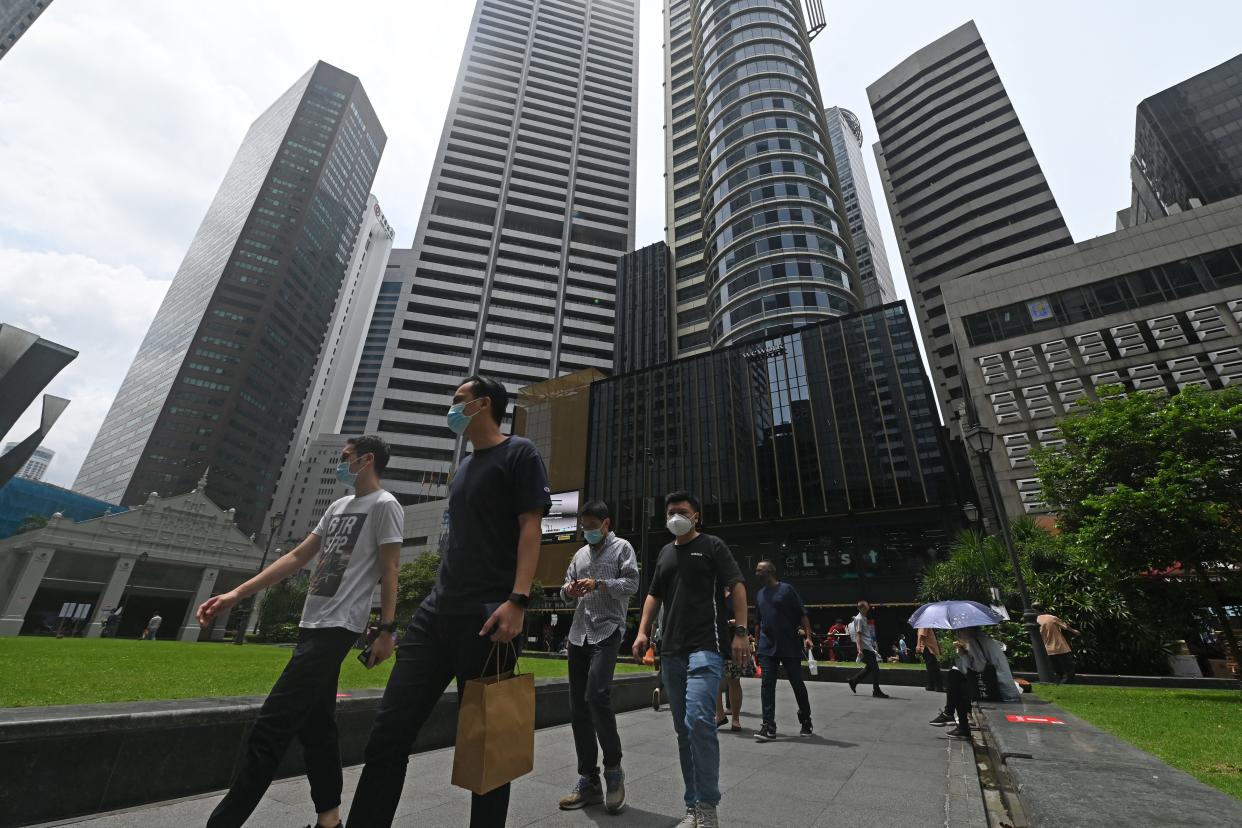 Office workers walk out during their lunch break at Raffles Place in Singapore, illustrating a story on flexi-work arrangements such as WFH.