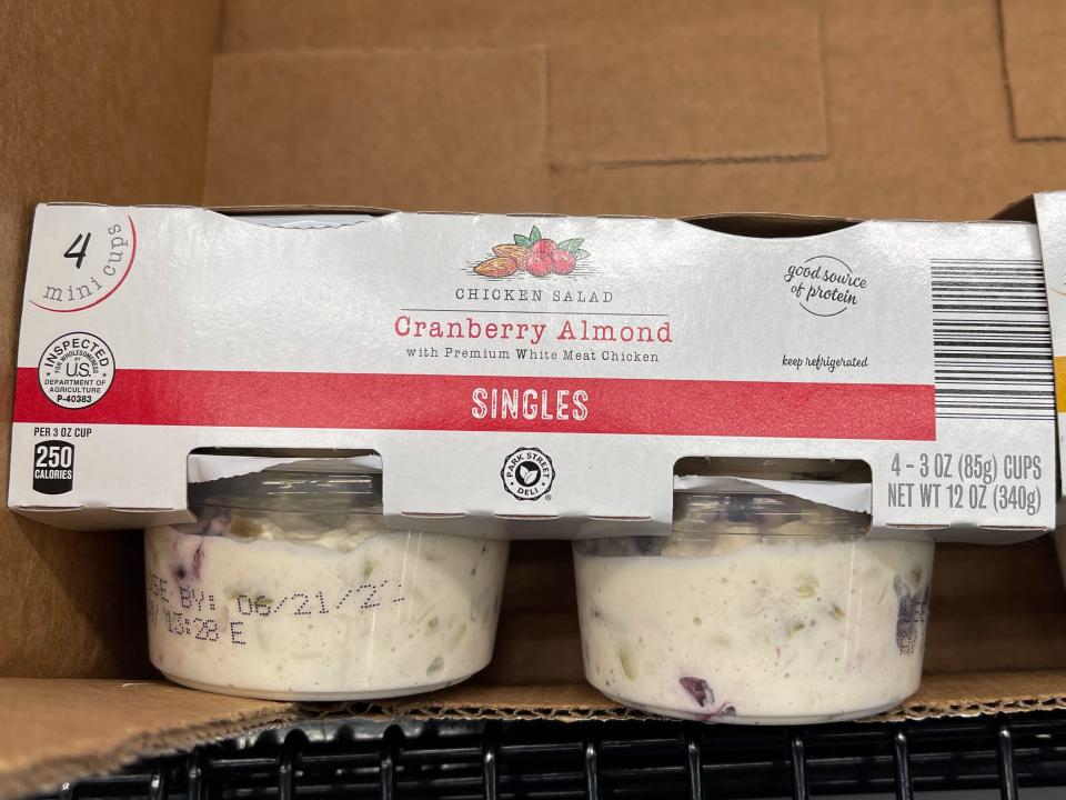 Two containers of chicken salad with gray cardboard packaging holding the two together