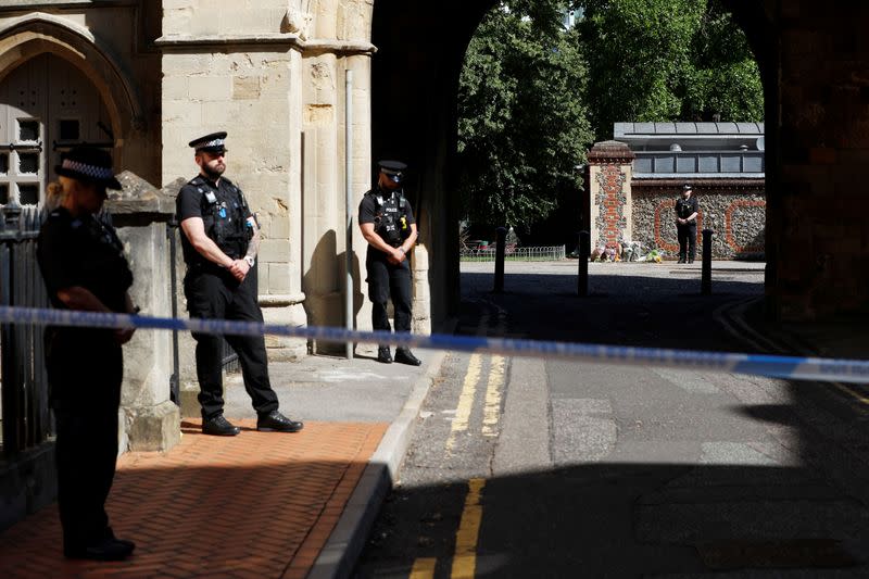 Police officers stand observing minute's silence near to the scene of reported multiple stabbings in Reading