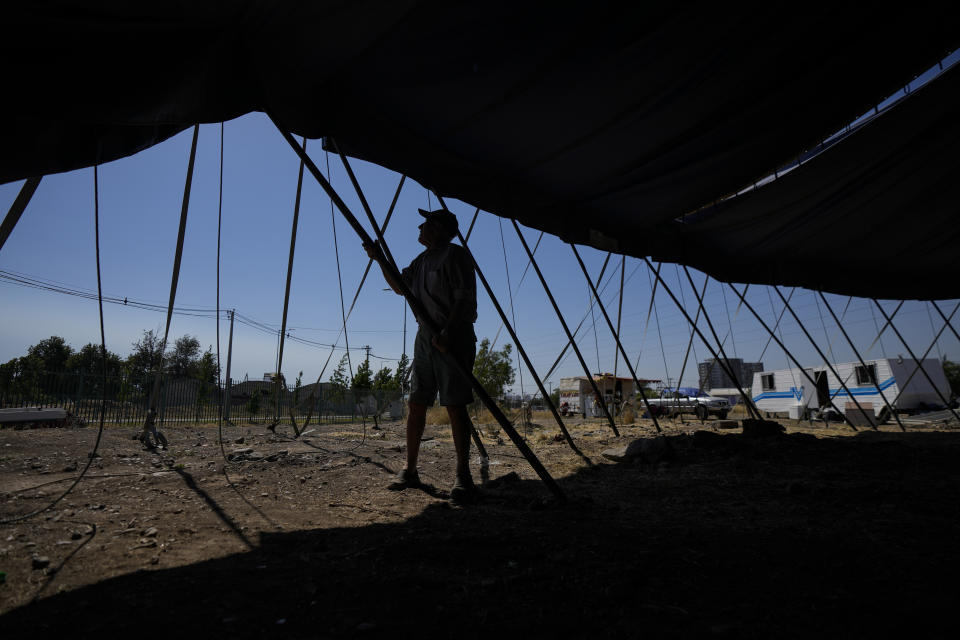 El fundador del Circo Timoteo, René Valdés, ayuda a desmontar la carpa para trasladarla a otra ciudad, a las afueras de Santiago, Chile, el 20 de diciembre de 2022. El espectáculo comenzó en 1968 de modo casual cuando a una función faltó una de las bailarinas Valdés animó a uno de los artistas a vestirse de mujer y sustituirla en el escenario. El espectáculo gustó tanto que acabó saliendo cinco veces a saludar y recibir aplausos. Allí nació el circo de transformismo. (AP Foto/Esteban Félix)